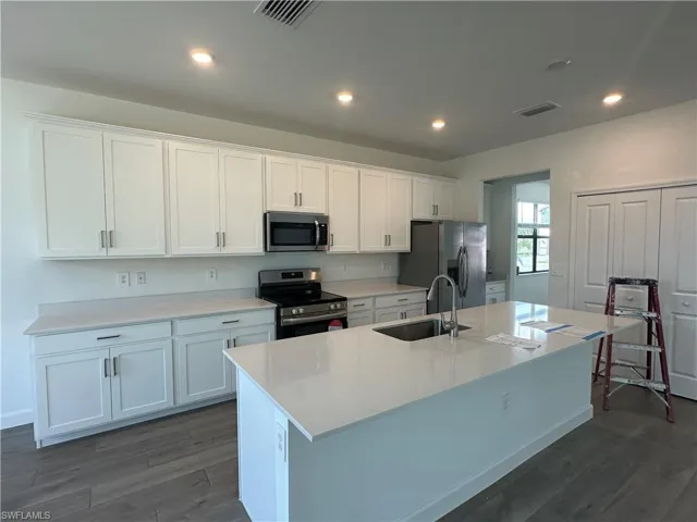 Kitchen with stainless steel appliances, sink, an island with sink, and white cabinets