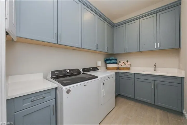 Laundry area featuring independent washer and dryer, cabinet space, and light wood-style floors