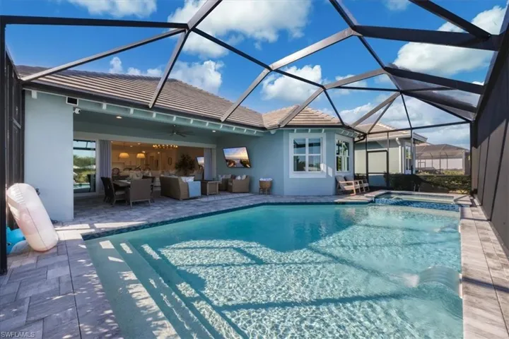 Integrated pool / hot tub with a sunroom, a patio, glass enclosure, and an outdoor living / dining area