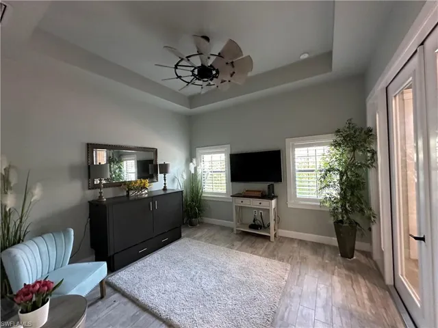 Sitting room with ceiling fan, light hardwood / wood-style flooring, and a raised ceiling