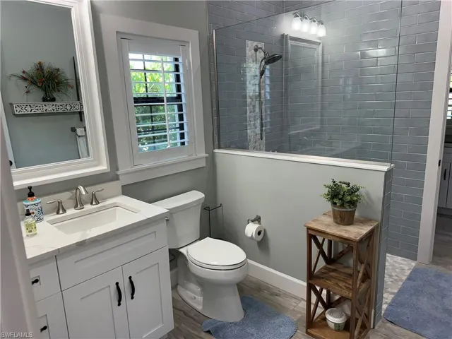 Bathroom featuring a tile shower, vanity, hardwood / wood-style floors, and toilet