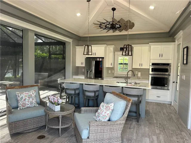 Kitchen with pendant lighting, stainless steel appliances, vaulted ceiling with beams, and hardwood / wood-style flooring