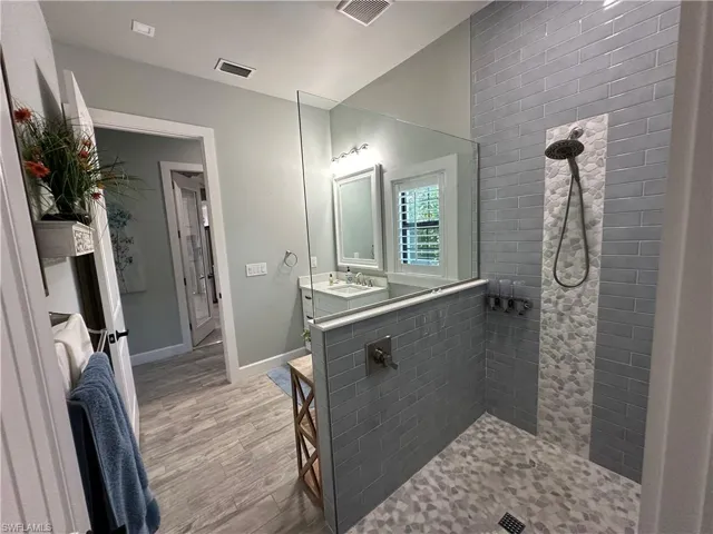 Bathroom featuring a tile shower, vanity, and hardwood / wood-style flooring