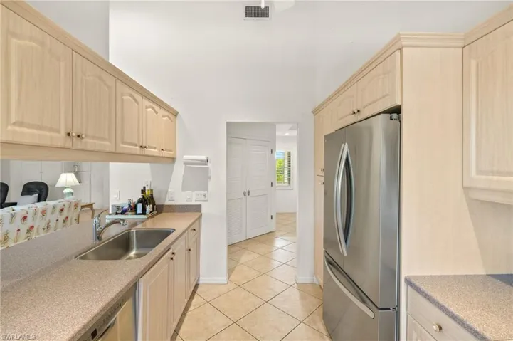 Kitchen featuring appliances with stainless steel finishes, light brown cabinetry, a sink, light tile patterned floors, and light countertops