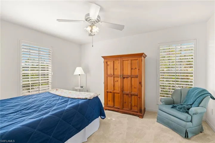 Bedroom with multiple windows, light colored carpet, and ceiling fan