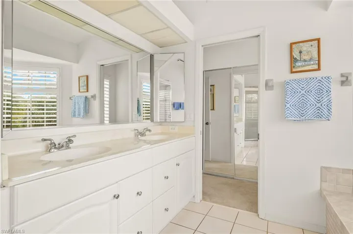 Bathroom with tile patterned floors, double vanity, and a tub to relax in