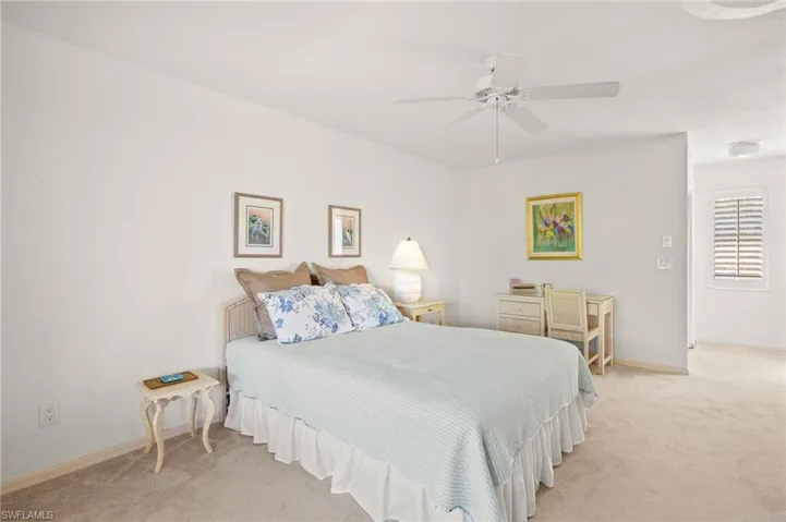 Bedroom featuring light colored carpet, baseboards, and a ceiling fan