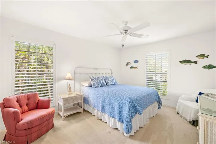 Bedroom with multiple windows, light carpet, ceiling fan, and baseboards