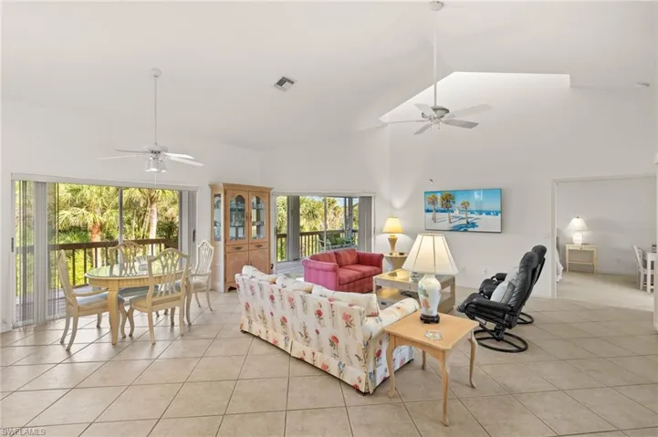 Living room featuring ceiling fan, light tile patterned flooring, and high vaulted ceiling