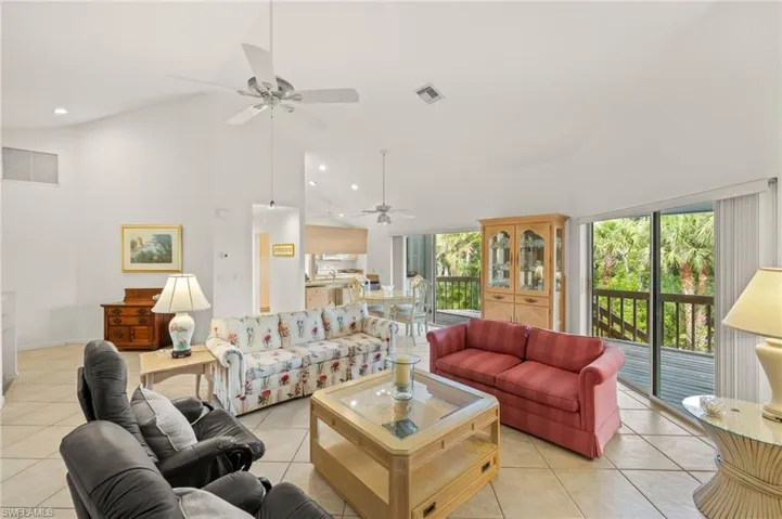 Living area with high vaulted ceiling, a ceiling fan, light tile patterned floors, plenty of natural light, and recessed lighting