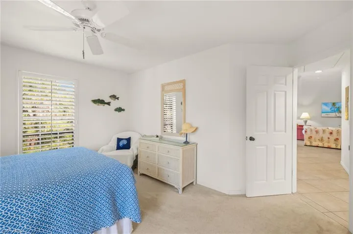 Bedroom with light colored carpet, baseboards, and a ceiling fan