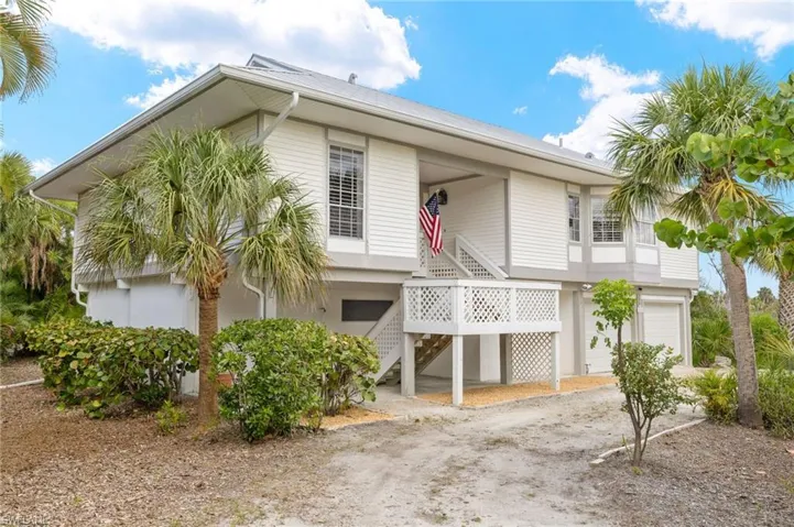 Beach home featuring stairway, driveway, an attached garage, and metal roof