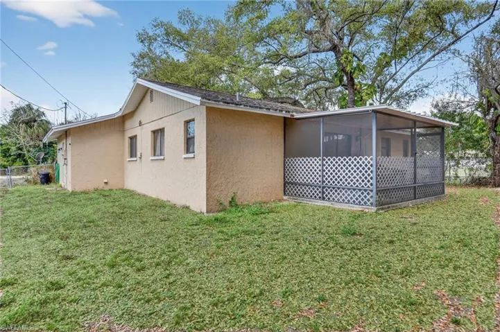 View of side of home featuring a sunroom, stucco siding, and a yard