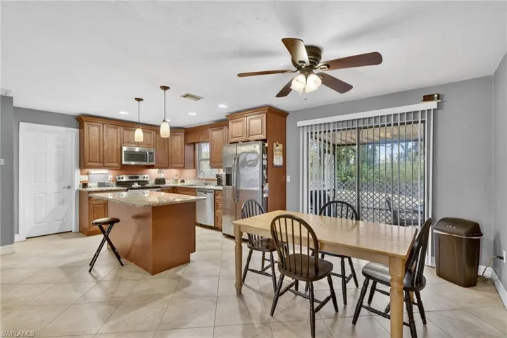 Kitchen featuring wood finish cabinets, light stone counters, a kitchen island, and stainless steel appliances