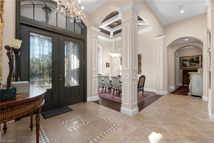 Tiled foyer entrance with french doors and beamed ceiling.