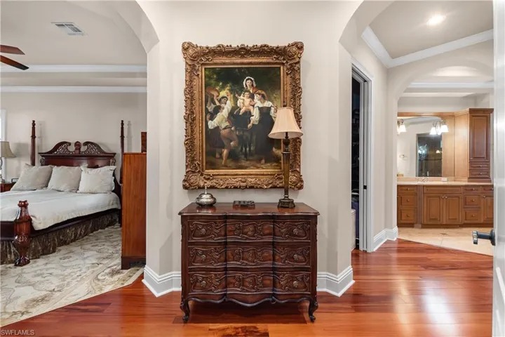 Bedroom featuring wood-type flooring, ensuite bathroom, ceiling fan, and crown molding