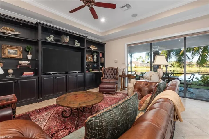 Tiled Family room featuring a tray ceiling, ceiling fan, ornamental molding and an expansive wall unit