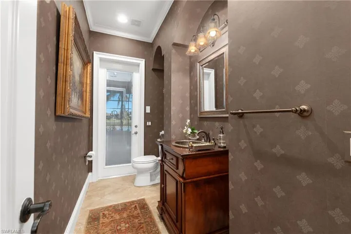 Bathroom featuring tile patterned flooring, vanity, toilet, and crown molding