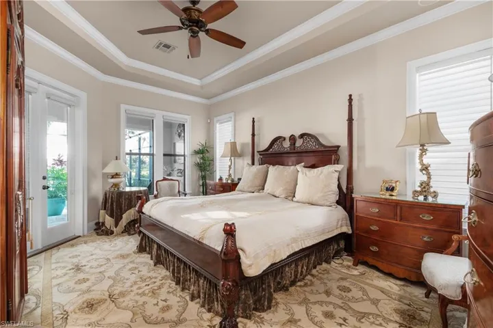 Bedroom with a raised ceiling, ceiling fan, access to exterior, and crown molding