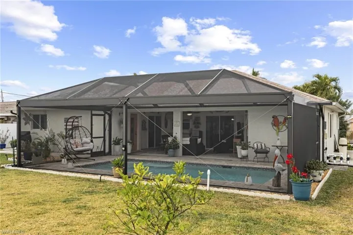 Rear view of house featuring an outdoor pool, a yard, a patio, and a sunroom