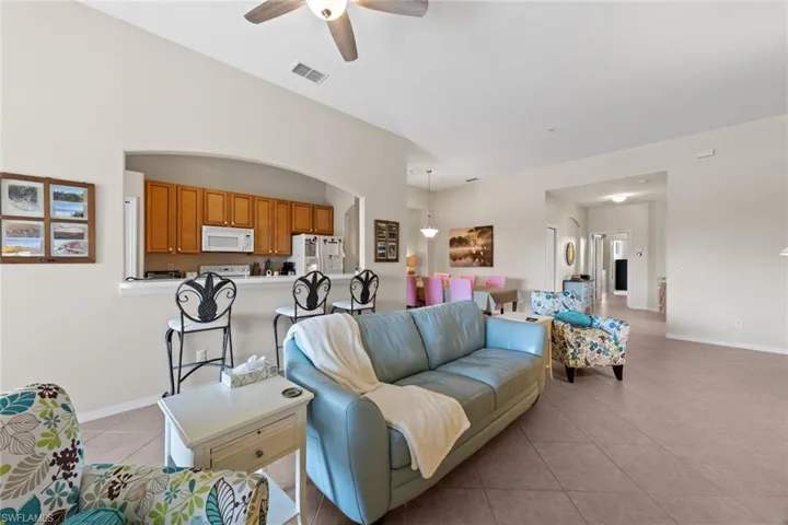 Living room with visible vents, a ceiling fan, baseboards, and light tile patterned floors