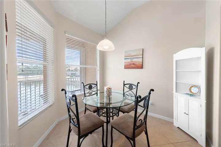 Dining area with vaulted ceiling, baseboards, and light tile patterned floors
