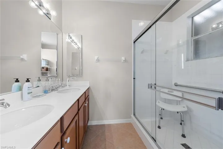 Full bathroom with double vanity, tile patterned floors, a stall shower, and a sink