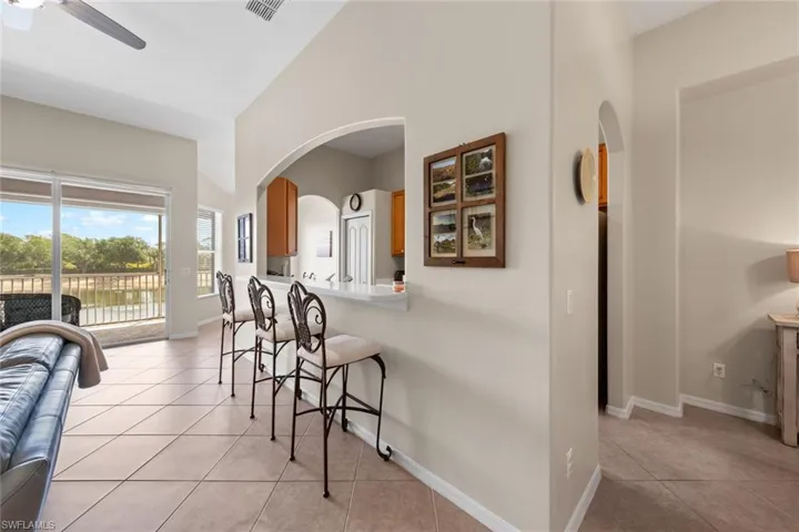 Kitchen featuring visible vents, light tile patterned floors, a kitchen bar, brown cabinetry, and ceiling fan