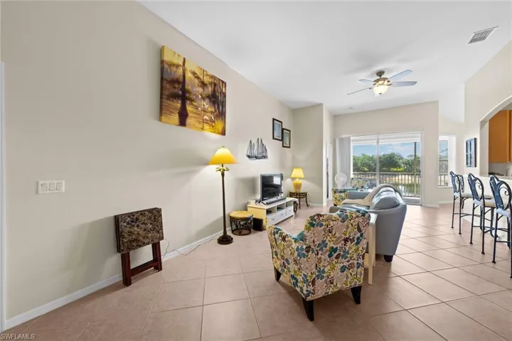 Living area with ceiling fan, baseboards, light tile patterned flooring, and visible vents