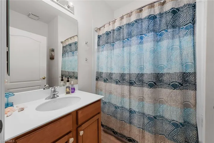 Full bath featuring vanity, curtained shower, and visible vents