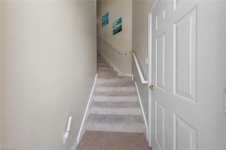 Staircase featuring carpet flooring, baseboards, and tile patterned floors