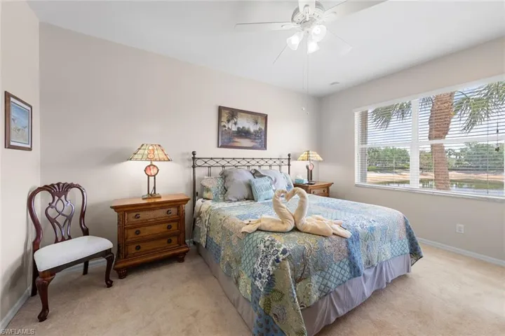 Bedroom featuring baseboards, a ceiling fan, and light colored carpet