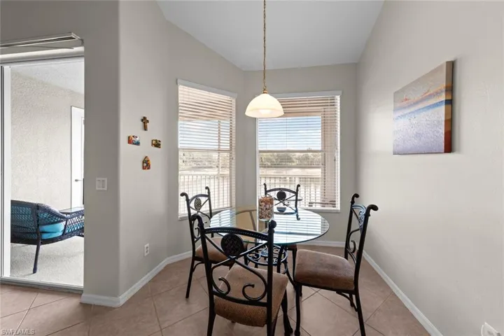 Dining area with vaulted ceiling, baseboards, and light tile patterned floors