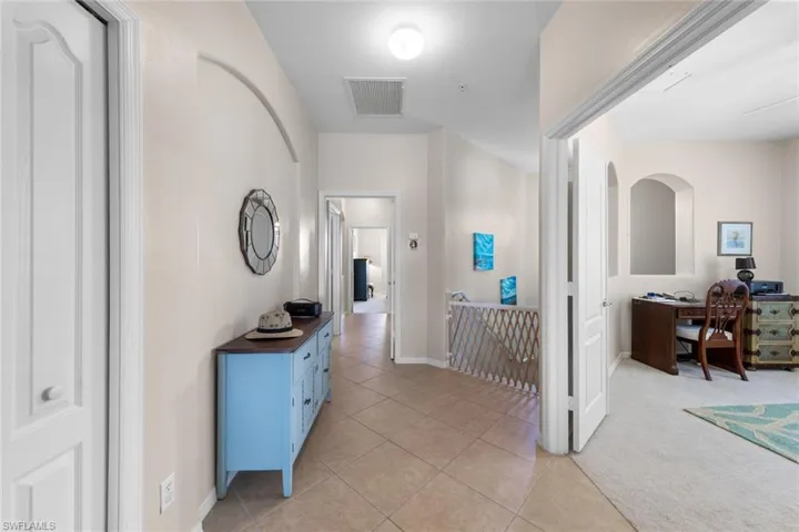 Hall featuring baseboards, visible vents, an upstairs landing, and light tile patterned floors