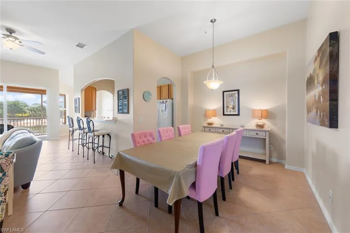 Dining area with ceiling fan, arched walkways, visible vents, and light tile patterned floors