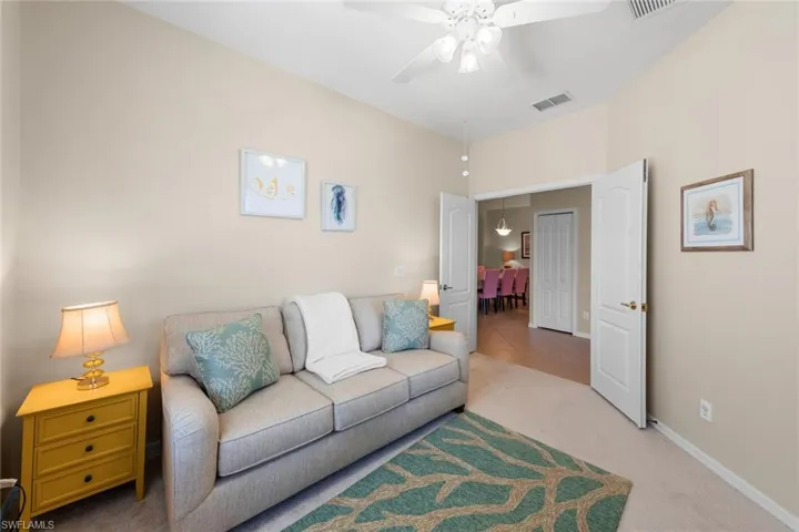 Living area featuring carpet floors, a ceiling fan, visible vents, and baseboards