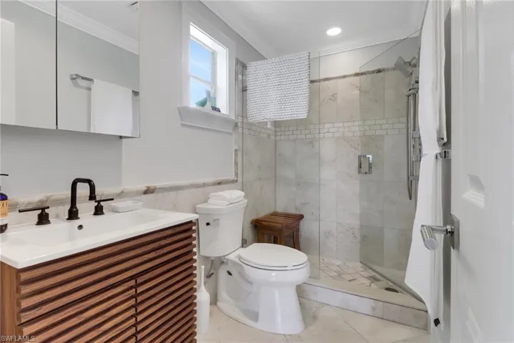 Master Bathroom featuring crown molding, vanity, a shower stall, wainscoting, and tile walls