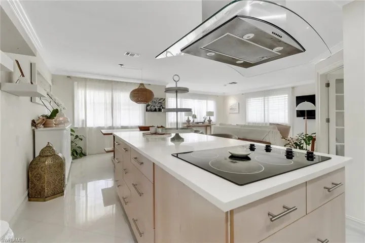Kitchen featuring extractor fan, black electric cooktop, crown molding, a kitchen island, and light countertops