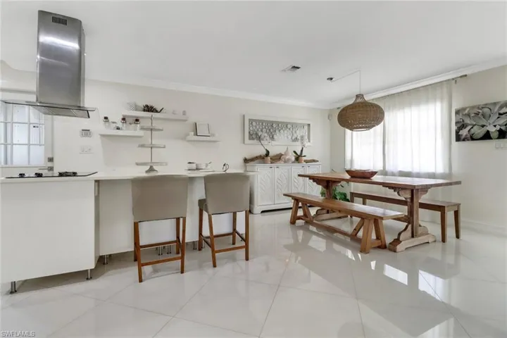 Kitchen featuring plenty of natural light, range hood, ornamental molding, white cabinets, and light tile patterned floors