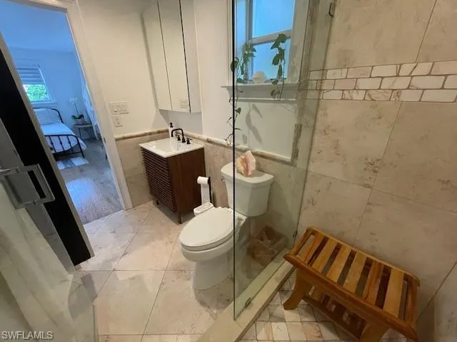 Master Full bath with vanity, tile walls, plenty of natural light, wainscoting, and connected bathroom