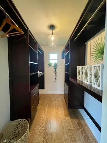 Spacious custom closet featuring wood finished floors