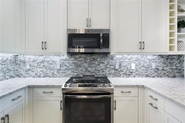 Kitchen with white cabinets, appliances with stainless steel finishes, and backsplash