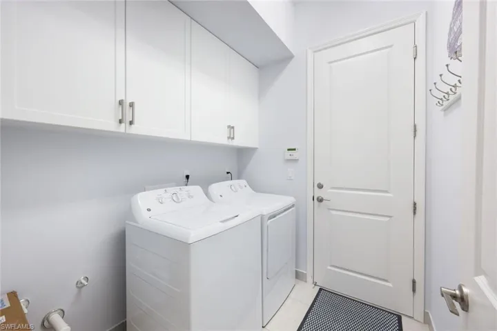 Laundry room with washer and clothes dryer, cabinets, and light tile patterned floors