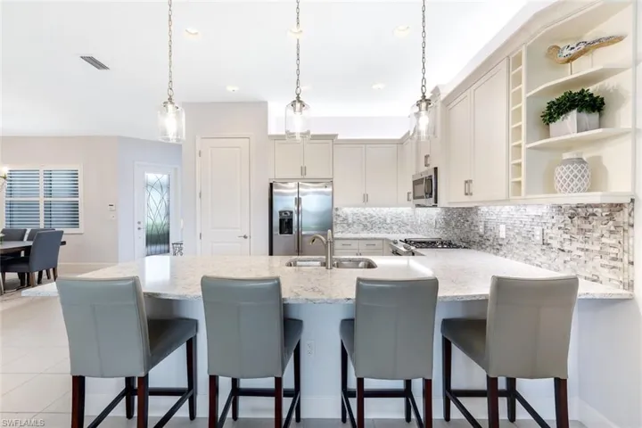 Kitchen with stainless steel appliances, a kitchen bar, hanging light fixtures, and sink