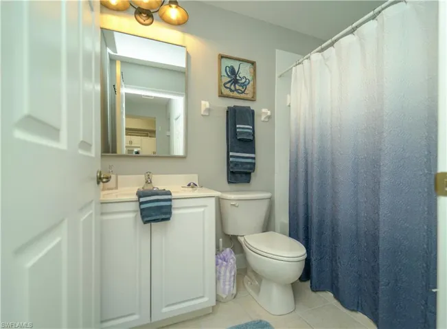 Bathroom featuring vanity, light tile patterned floors, and shower / bath combo with shower curtain