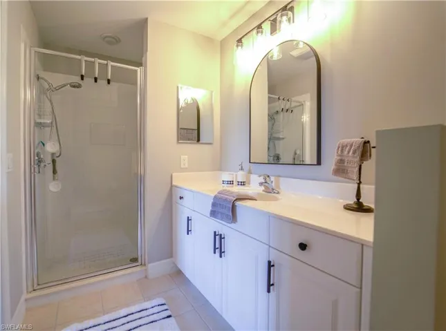 Full bath featuring vanity, a shower stall, and light tile patterned floors