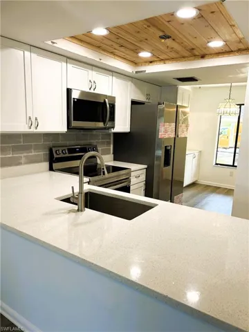 Kitchen with light stone countertops, recessed lighting, wood ceiling, appliances with stainless steel finishes, and backsplash
