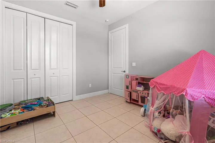 Bedroom featuring light tile patterned floors, ceiling fan, and a closet