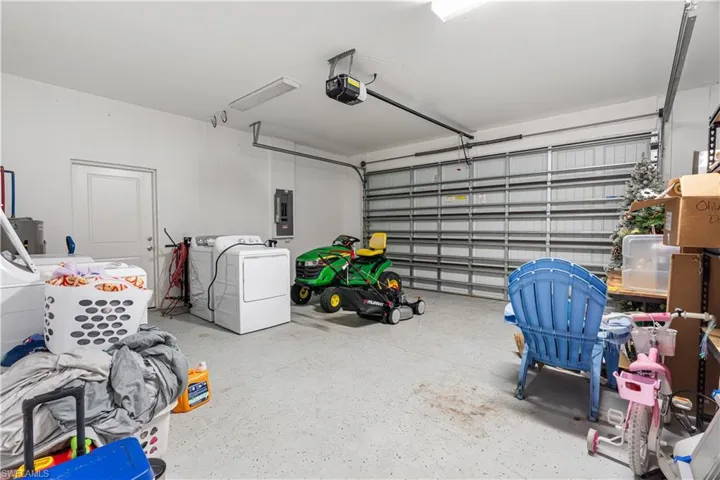 Garage featuring a garage door opener, electric panel, and washer and dryer