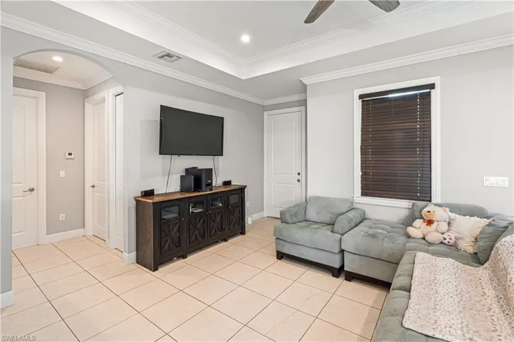 Tiled living room with crown molding and ceiling fan